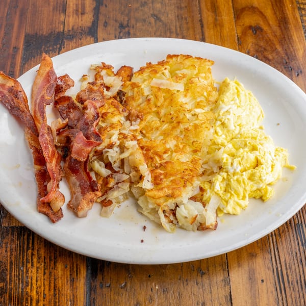 A diner breakfast plate with crispy bacon, golden hash browns, and fluffy scrambled eggs.