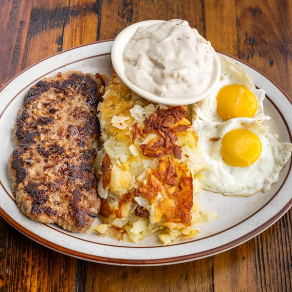 Crazy Otto's Diner breakfast with two sausage patties, hash browns, two fried eggs, and gravy.