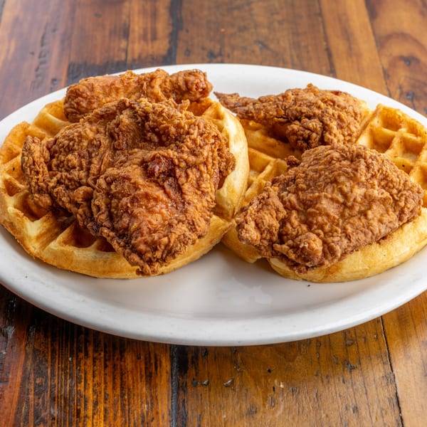 Crispy fried chicken pieces served on golden waffles on a white plate at Crazy Otto's Diner.